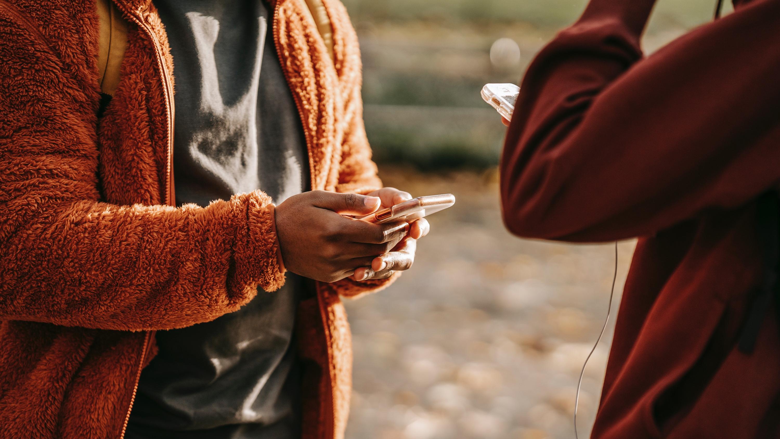 Two people holding and using smartphones