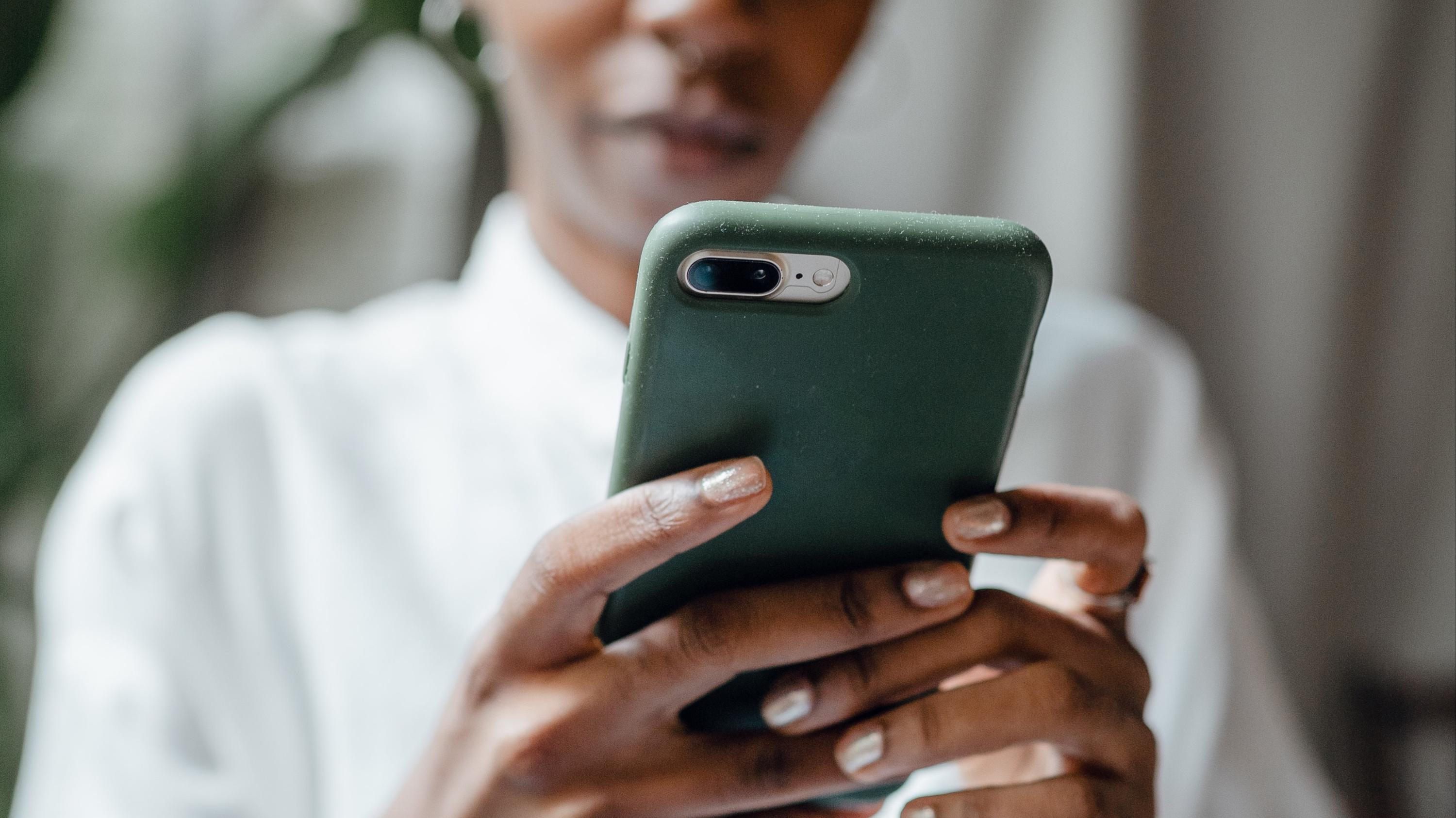 Woman holding her smartphone out and looking at it