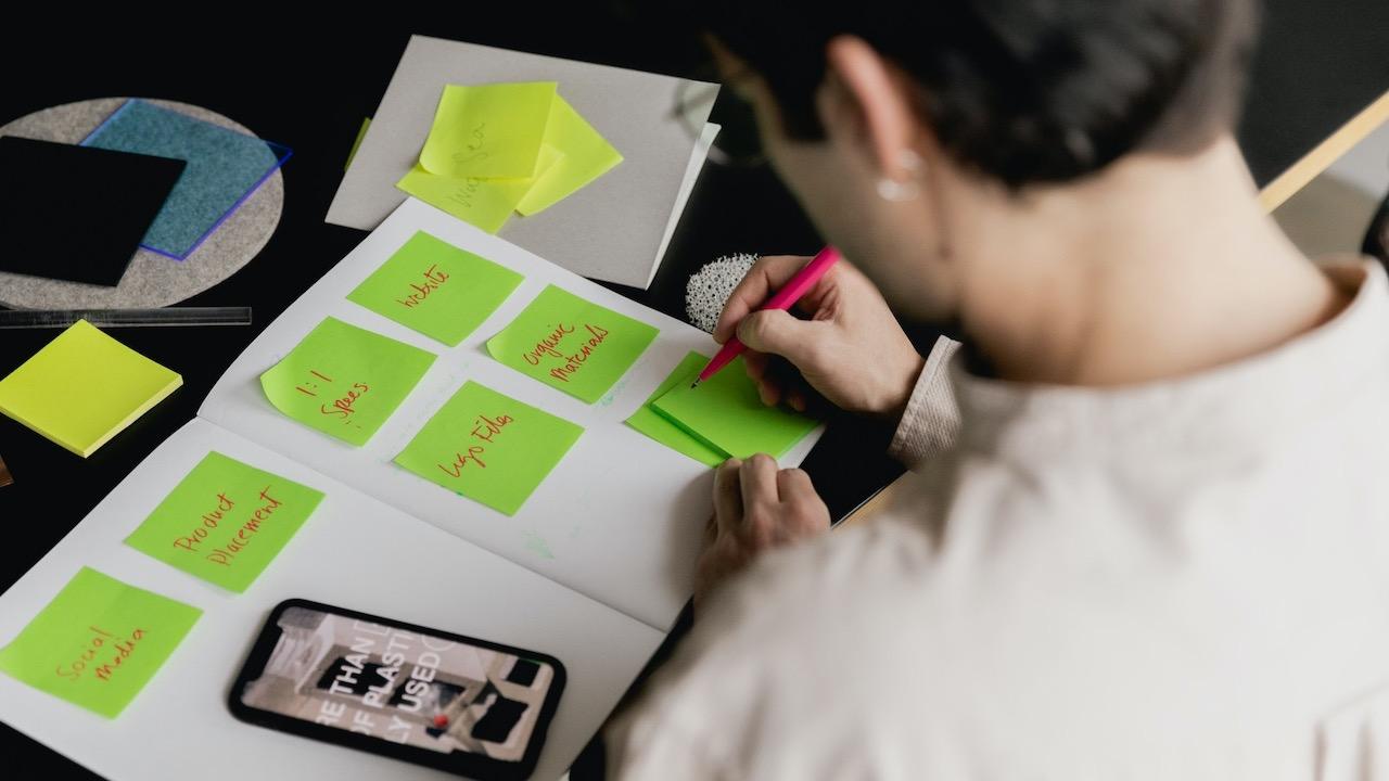 Someone writing things on a green sticky note